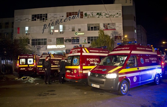 Ambulances are parked outside the site of an explosion that occurred in a club, housed by the building in the background, in Bucharest, early Saturday, Oct. 31, 2015. An explosion and ensuing flames on a stage at a Bucharest nightclub on Friday left more than 20 people dead and over 150 hospitalized with injuries, Romania's interior minister said. (AP Photo/Vadim Ghirda).