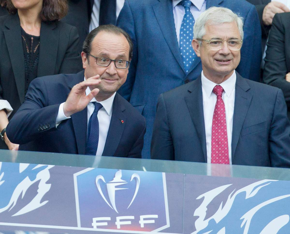 French president Francois Hollande, left, and French National Assembly Speaker Claude Bartolone, right, take their seats prior to the French Cup final soccer match between Paris Saint-Germain (PSG) and Auxerre at the Stade de France Stadium, in Saint Denis, north of Paris, Saturday May 30, 2015.