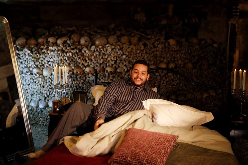 Guest Brazilian Pedro Arruda, 27, poses in the bed prior to spend the Halloween night with his mother Monica in Paris' creepy Catacombs amid skulls and bones, in Paris, France, Saturday, Oct, 31, 2015.