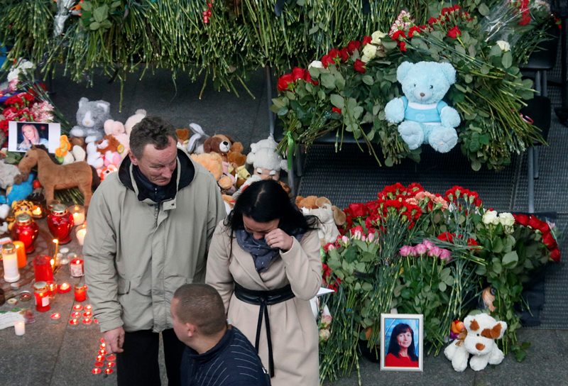 A couple react as they come to lay flowers and toys at an entrance of Pulkovo airport outside St.Petersburg, Russia, during a day of national mourning for the plane crash victims, on Sunday, Nov. 1, 2015.