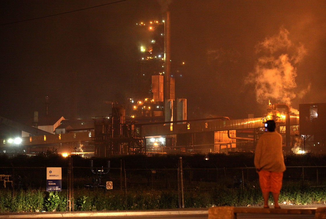 A woman stands looking at the No. 7 blast furnace at Essar Steel Algoma in Sault Ste. Marie, Ontario.