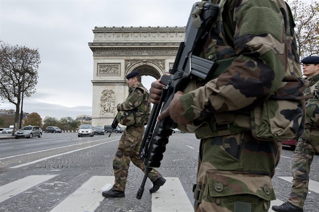 French soldiers cross the Champs Elysees avenue passing the Arc de Triomphe in Paris, Monday, Nov. 16, 2015. 