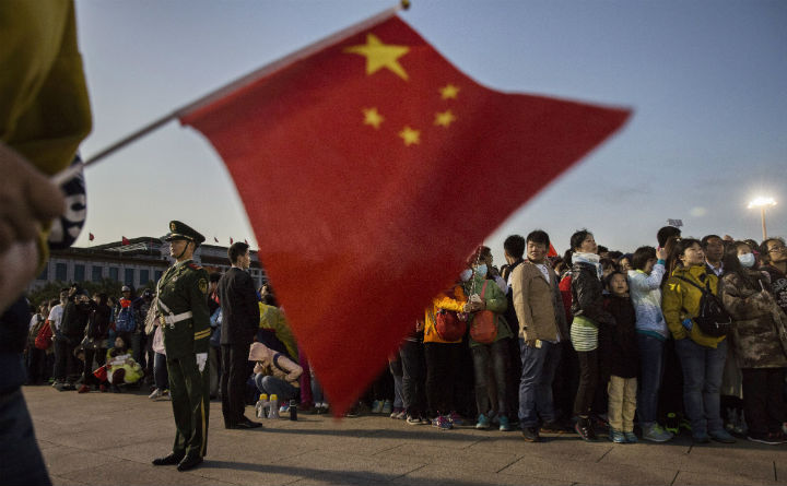  A Chinese paramilitary police officer stands guard as crowds gather at the official flag raising ceremony at Tiananmen Square to mark the 66th National Day on October 1, 2015 in Beijing, China.