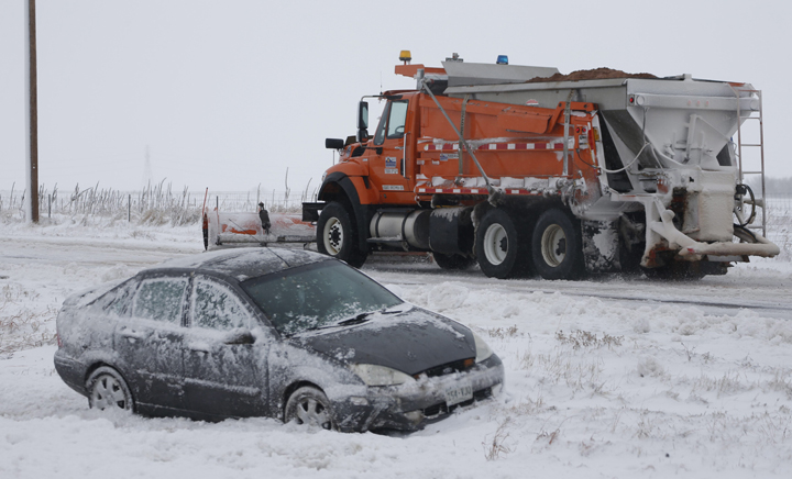 A sedan sits stranded along Interstate 70 while a Colorado Department of Transportation plow works to clear a road as a winter storm packing high winds and snow blankets the plains Tuesday, Nov. 17, 2015, in Aurora, Colo. 