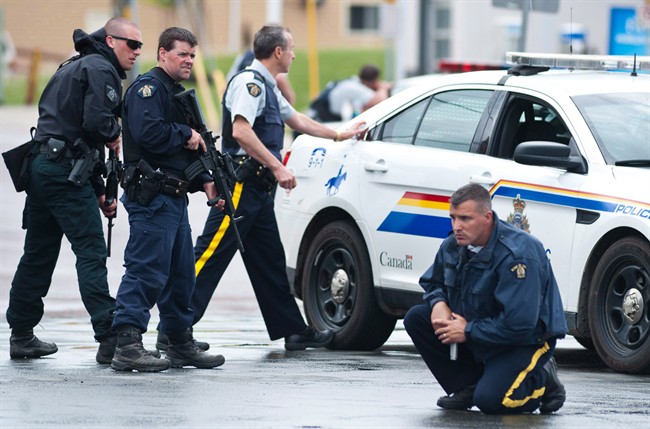 Police keep watch on a house as they search for a heavily armed gunman following the shooting of three Mounties in Moncton, N.B., on June 5, 2014. RCMP representatives are expected in court in Moncton, N.B., today for a hearing on alleged violations of the Canada Labour Code related to the force's response to a deadly shooting rampage last year. Employment and Social Development Canada alleges there were four violations of the code relating to the force's equipment, training and supervision in the June 4, 2014 incident that terrorized the New Brunswick city and resulted in the deaths of three Mounties. 