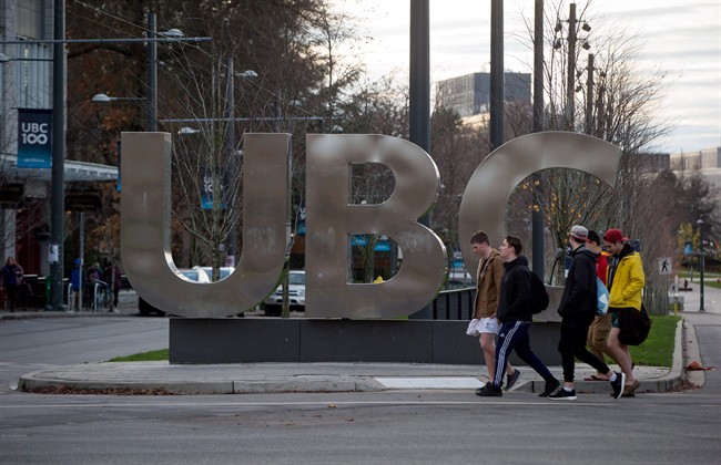 Young men walk past large letters spelling out UBC at the University of British Columbia in Vancouver, B.C., on November 22, 2015.