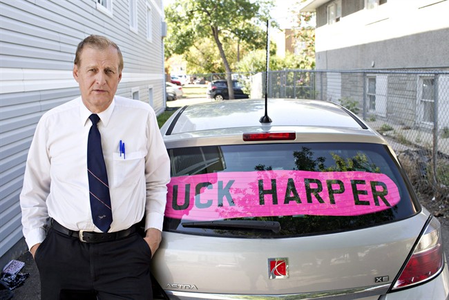Rob Wells stands with his Steven Harper sign he put in his vehicle's rear window in Edmonton Alta, on Wednesday Aug 19, 2015. An Edmonton man who was issued a $543 fine for putting a sign in his car window with an expletive aimed at former prime minister Stephen Harper says his case is being bumped up to provincial court. 
