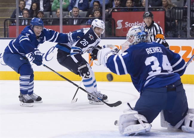 Winnipeg Jets' Blake Wheeler, centre, shoots wide on Toronto Maple Leafs' goaltender James Reimer, right, as defenceman Matt Hunwick pushes him away from a rebound during first period NHL hockey action, in Toronto, on Wednesday, Nov. 4, 2015. THE CANADIAN PRESS/Darren Calabrese.