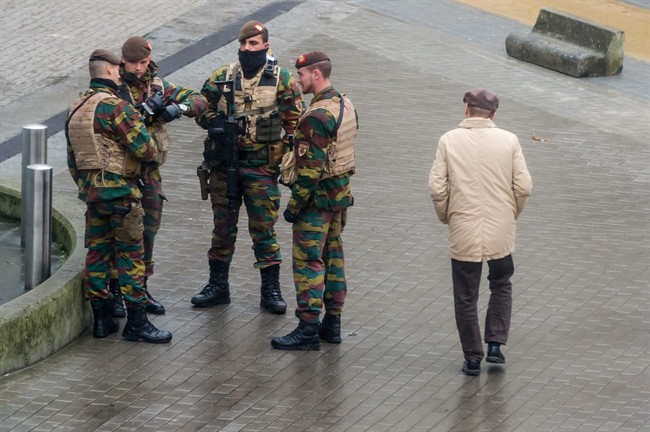 A man walks by Belgian soldiers guarding the entrance to the European Commission headquarters in Brussels on Tuesday, Nov. 17, 2015.