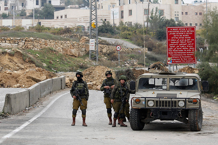 Israeli soldiers stand guard at a military blocked road in the West Bank city of Hebron, Saturday, Nov. 7, 2015. 