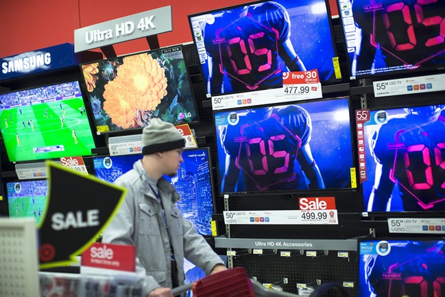 A holiday shopper browses the electronics section against a backdrop of televisions at a Target store Friday.