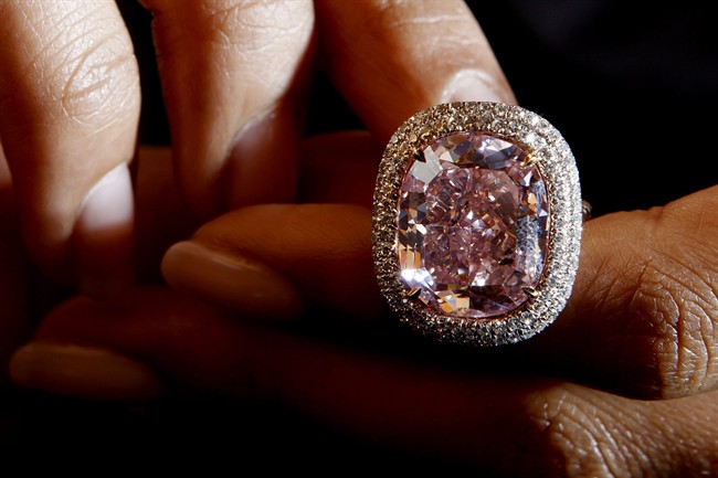 In this Oct. 30, 2015 file photo a Christie's employee presents a cushion-shaped fancy Vivid Pink diamond of 16.08 carats, during a preview at the Christie's auction house in Geneva, Switzerland, Friday, Oct. 30, 2015. The vivid diamond is estimated between 23 to 28 million US Dollars and will be sold during the Christie's auction Nov. 10 in Geneva.