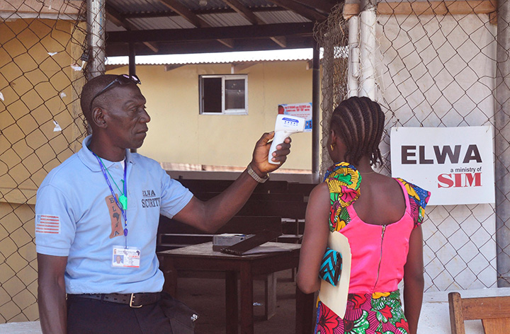 A unidentified family member, right, of a 10-year old boy that contracted Ebola, has her temperature  measured by a health worker before entering an Ebola on the outskirts of Monrovia, Liberia on Friday, Nov. 20, 2015. 