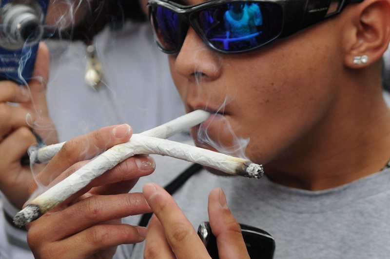 A youth smokes a cross-shaped marijuana cigarette during a march in favor of the legalization of marijuana in Medellin, Colombia.