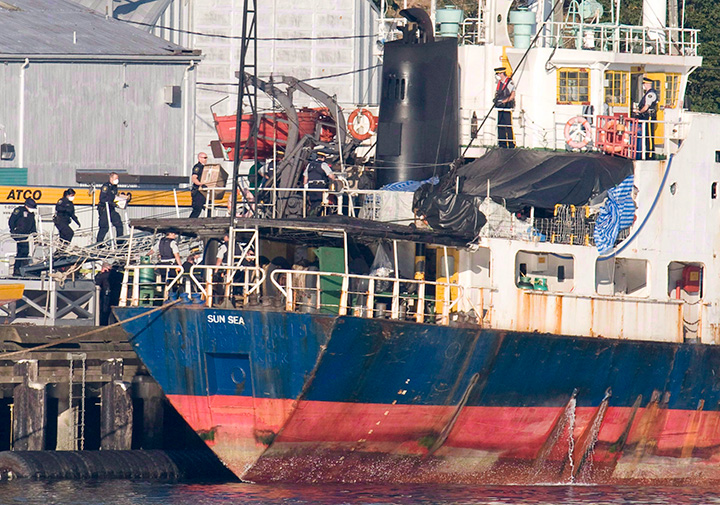 Police and military personnel wear surgical masks as they board the MV Sun Sea after it was escorted into CFB Esquimalt in Colwood, B.C., on Aug. 13, 2010.