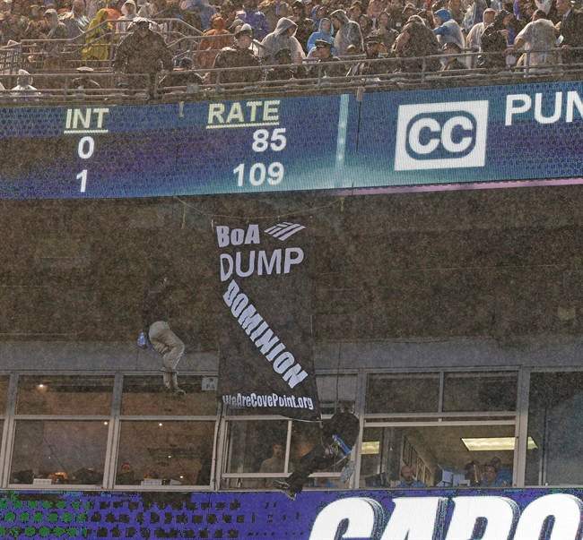 A police officer looks from above as two people hang a banner from the upper deck of Bank of America stadium in the second half of an NFL football game between the Carolina Panthers and the Indianapolis Colts in Charlotte, N.C., Monday, Nov. 2, 2015. 