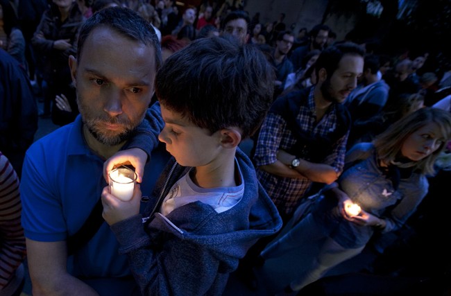 FILE- In this Monday, Nov. 16, 2015, file photo, a man holds a child in his arms outside of the French embassy in Mexico City during a vigil for the victims of the terrorist attacks in Paris. After the France terror attacks, schools and parents around the world are grappling with what to say to children, and how to say it. From country to country, the topic was tackled in different ways. 