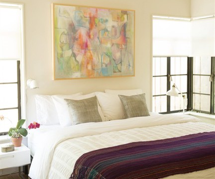 In this photo provided by Apartment Therapy, LLC, this bedroom, depicted in designer Maxwell Ryan’s book "Apartment Therapy: Complete Happy Home," features a large, boldly colored painting over the bed, contrasted with light, neutral walls. In a small room, an oversized piece of dramatic art can actually give the feeling of more space, says Ryan.