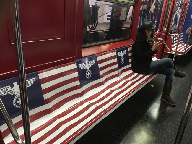 A woman uses her cellphone while sitting on a seat covered in Nazi imagery in a New York City subway car in New York.