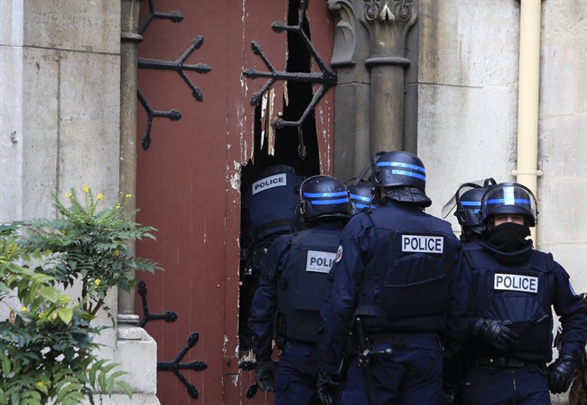 French police officers storm a church after a raid in Paris suburb Saint-Denis, Wednesday, Nov.18, 2015.