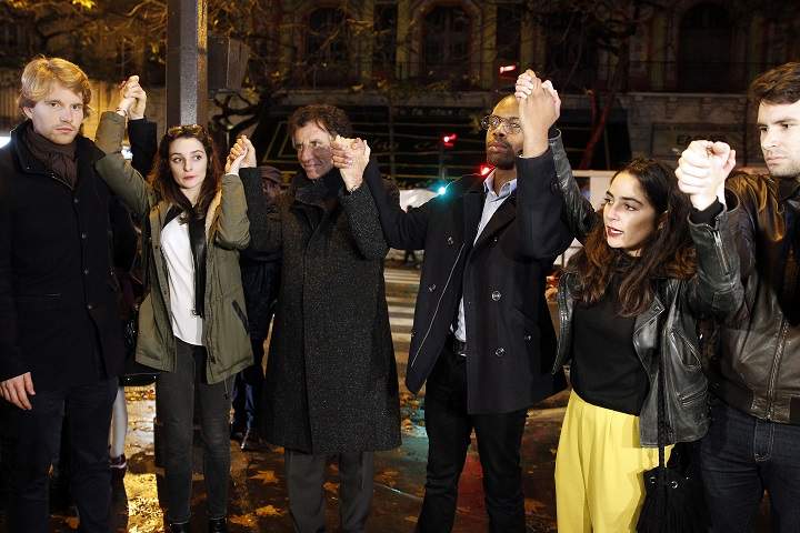 France's former Minister of Culture and current President of the Institude of the Arab World Jack Lang (C) holds hands with members of the public at a memorial set-up near the Bataclan theatre on November 20, 2015 in Paris, France.
