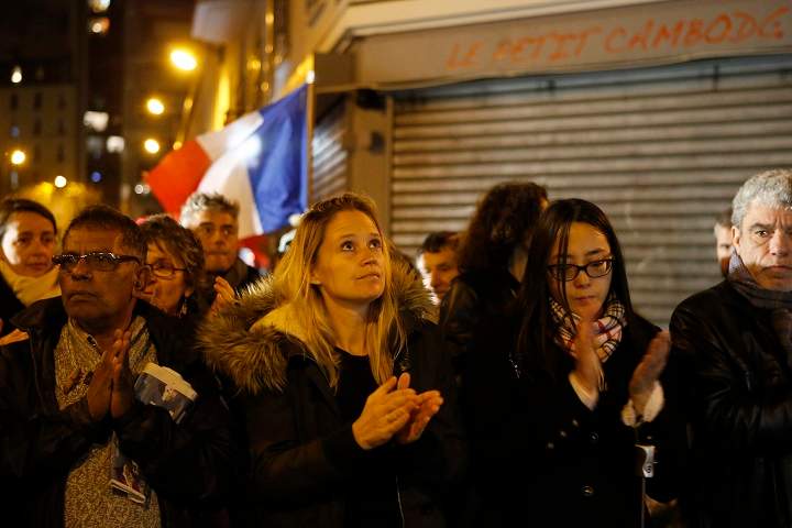 People applaud at 9:20 p.m., the time the attacks began on Nov. 13 in front of "The Petit Cambodge" Restaurant, one of the site of most deadly of six coordinated extremists attacks, in Paris, France, Friday, Nov. 20, 2015. French artists and cultural figures are calling for people to mark a week since the start of the Paris attacks with an outpouring of "noise and light".