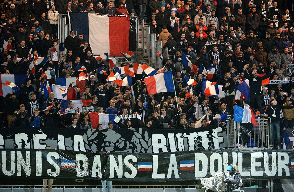 Angers' supporters cheer for their team behind a banner reading "United in pain" in reference to the November 13 terror attacks in Paris before the start of the French L1 football match between Angers and Lille at the Jean Bouin Stadium in Angers, western France, on November 28, 2015.