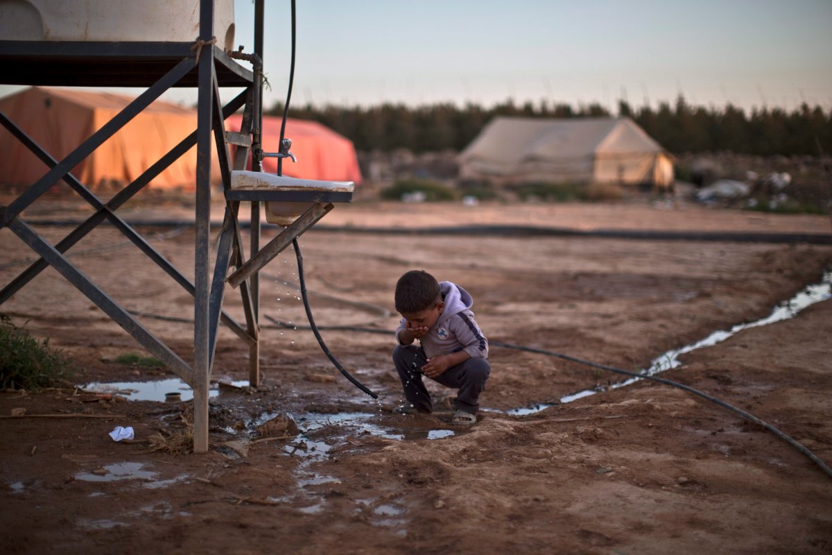 A Syrian refugee child drinks water from a pipe at an informal tented settlement near the Syrian border on the outskirts of Mafraq, Jordan, Wednesday, Oct. 21, 2015.