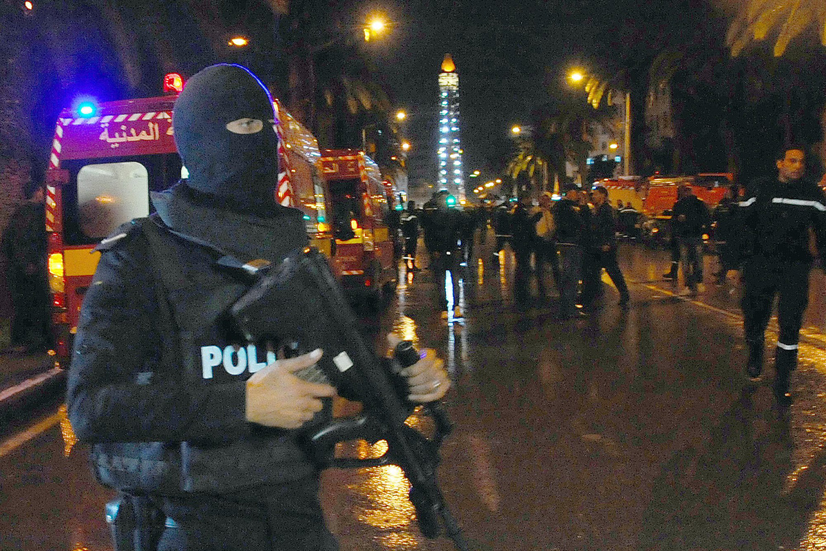 A hooded police officer prevents media from aproaching the scene of a bus explosion in the center of the capital, Tunis, Tunisia, Tuesday, Nov. 24, 2015. 