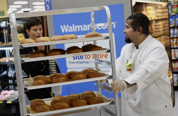 A bakery employee pushes a cart of baked rolls.
