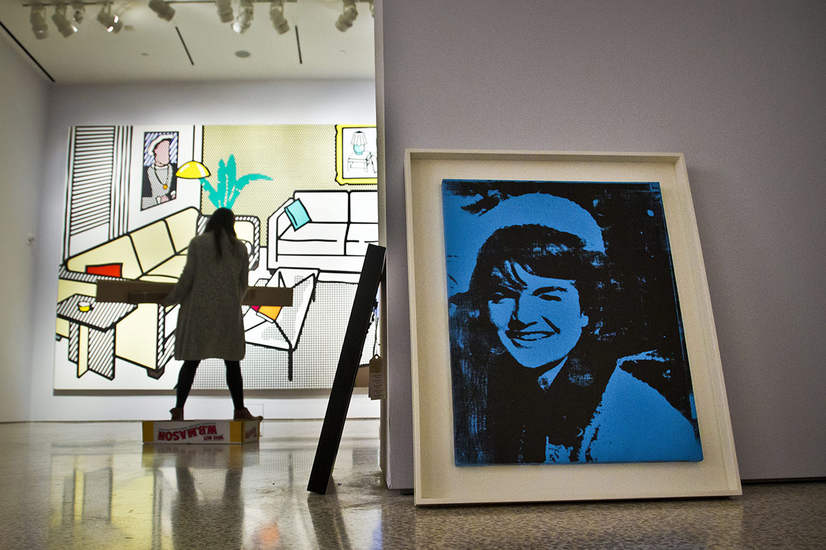 Andy Warhol's "Blue Jackie," right, and Roy Lichtenstein's "Interior with Yves Klein Sculpture," left, are among master works being installed at Christie's for the upcoming New York evening art auctions of impressionist, modern and post-war art, during a press preview, Friday Oct. 30, 2015, in New York. 