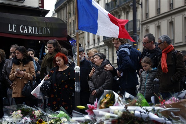 People gather in front of Le Carillon cafe, a site of the recent attacks, in Paris, Monday Nov. 16, 2015. French President Francois Hollande says the Paris attacks targeted "youth in all its diversity" and that the victims were of 19 different nationalities.