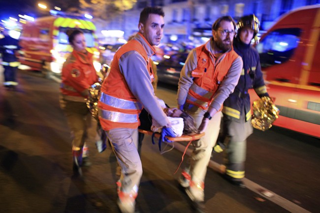  In this Nov.13, 2015 file photo, a woman is being evacuated from the Bataclan concert hall after a shooting in Paris. 