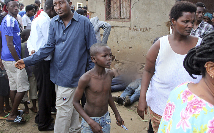 A young boy joins other onlookers at the scene where five dead bodies, seen behind, were found in a street in the Cibitoke neighborhood of the capital Bujumbura, Burundi.