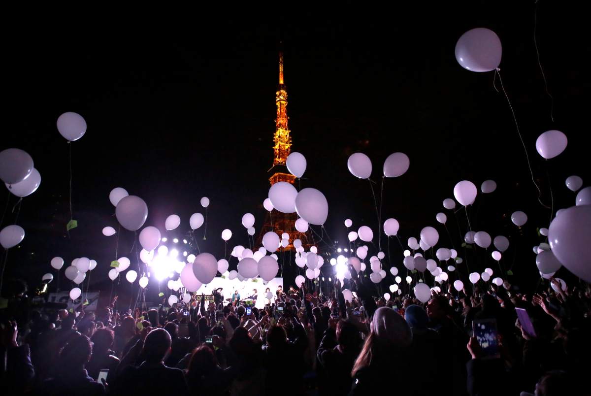 Peoples release balloons to celebrate the New Year with Tokyo Tower in the background in Tokyo, early Friday, Jan. 1, 2016. Japan celebrated the start of 2016, the Year of the Monkey in the Japanese Zodiac.