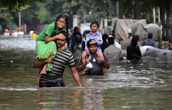 Indian residents carry children as they walk through floodwaters in Chennai on December 3, 2015.  Thousands of rescuers raced to evacuate residents from deadly flooding, as India's Prime Minister Narendra Modi went to the southern state of Tamil Nadu to survey the devastation. More than 40,000 people have been rescued in recent days after record rains lashed the coastal state, worsening weeks of flooding that has killed 269 people.