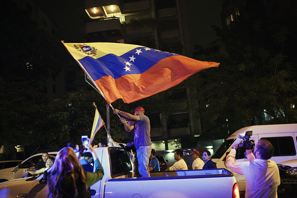 A man waves the Venezuelan national flag while standing in the back of a truck after hearing the results of the national congressional elections in Caracas, Venezuela, on Monday, Dec. 7, 2015. Venezuela's opposition alliance won a majority in Congress for the first time in 16 years in elections on Sunday as an unprecedented recession and a collapse in the bolivar turned voters against the populist policies of President Nicolas Maduro. 