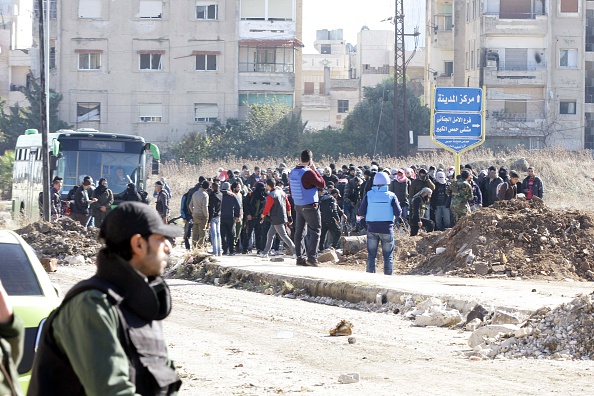 Members of the Syrian government forces stand guard as hundreds of civilians and Syrian rebel forces began evacuating the last opposition-held district of Waer in the central city of Homs, under a deal with the Syrian regime, on December 9, 2015. According to Talal Barazi, Homs governor, some 700 people -- including 400 women and children and 300 fighters -- would be evacuated from the district, after a deal reached earlier this month between rebel forces and Syrian President Bashar al-Assad's regime.