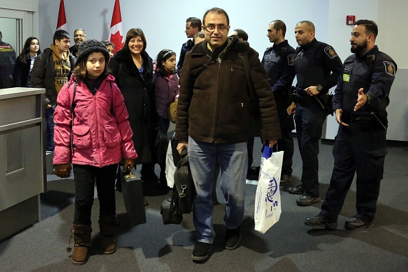 The first Syrian refugee family to disembark at Toronto Pearson International Airport makes their way into the Canada Border Services Agencys processing area on December 11, 2015. (Photo by Kenneth Allan/Canada Border Services Agency/Pool/Anadolu Agency/Getty Images).