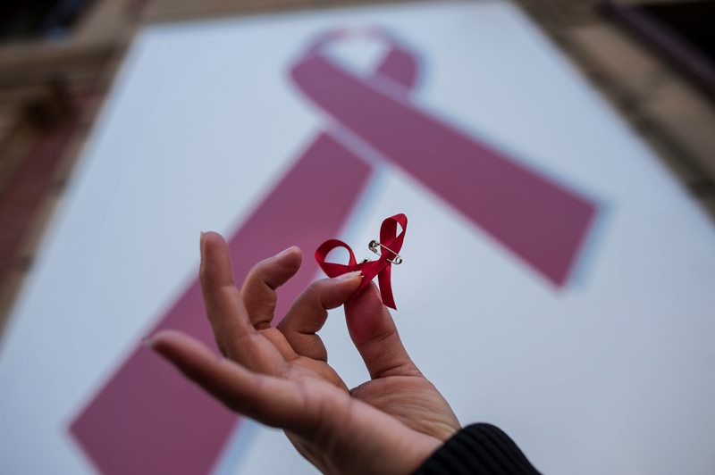 A woman holds a red ribbon symbol of the fight against AIDS during a demonstration on the World Aids Day, in  Spain, Tuesday, Dec. 1, 2015. 