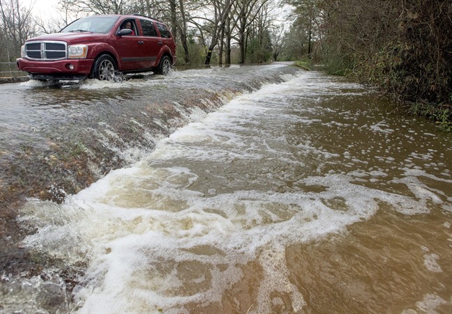 A vehicle drives along a flooded section of Hayneville Road in west Montgomery, Ala., on Christmas morning Friday, Dec. 25, 2015. The line of springlike storms continued marching east Thursday, dumping torrential rain that flooded roads in Alabama and caused a mudslide in the mountains of Georgia. 
