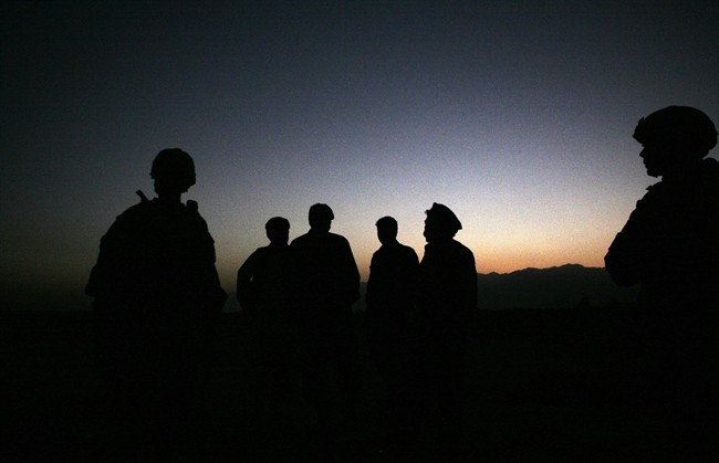 In this Sunday, Oct. 18, 2009 file photo, U.S. Army soldiers stand with Afghan policemen before a joint patrol of Qalanderkhail, outside of Bagram Air Field in Afghanistan. 