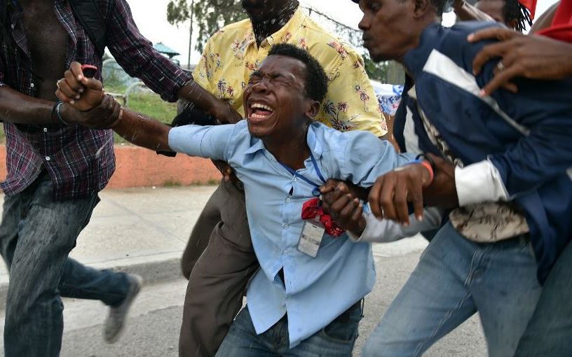 A Haitian journalist covering demonstrators protesting against the election results is overcome by tear gas fired by police in Port-au-Prince.