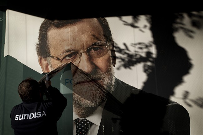 A worker removes a campaign poster for the national elections depicting Spain's acting Prime Minister and Popular Party candidate Mariano Rajoy, in Madrid, Monday, Dec. 21, 2015. 