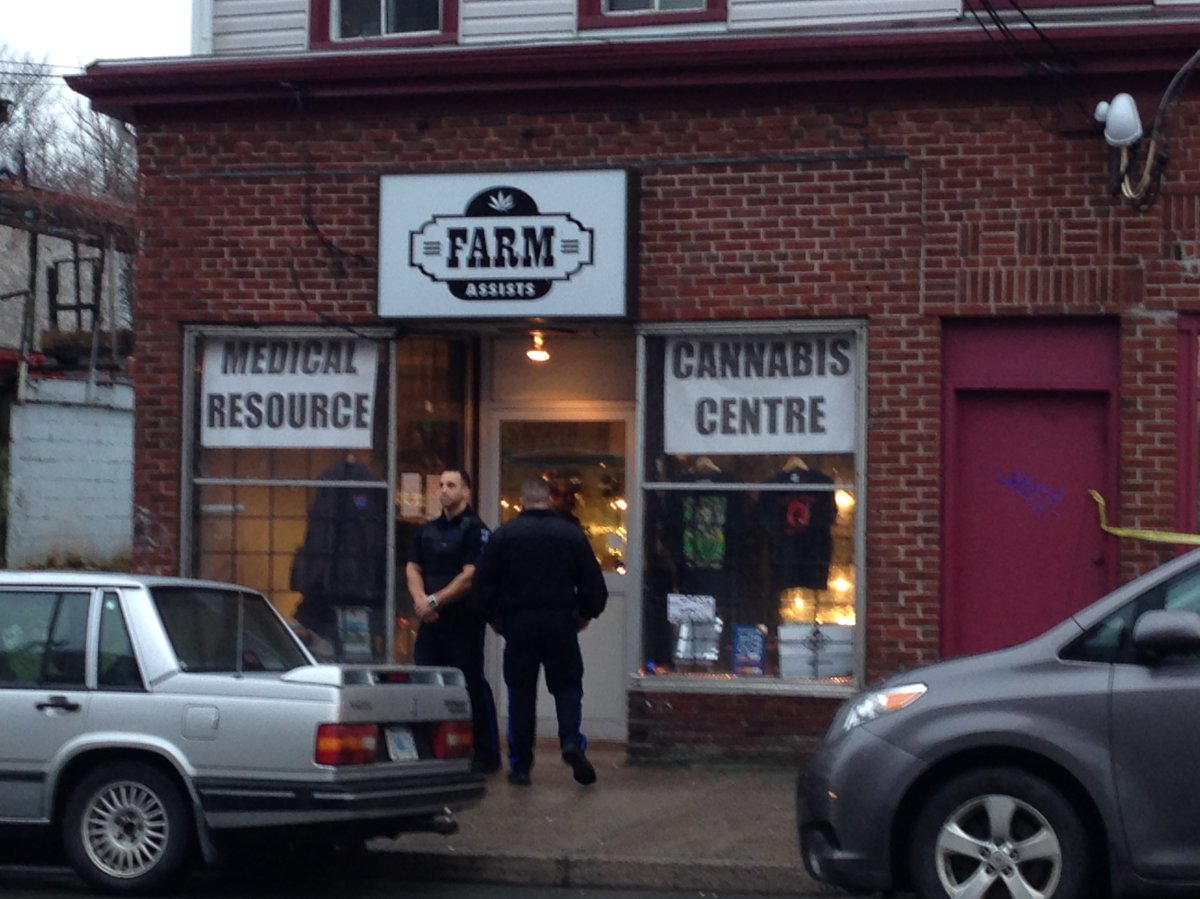 Police officers stand outside Farm Assists on Gottingen Street as officers execute an arrest warrant. 