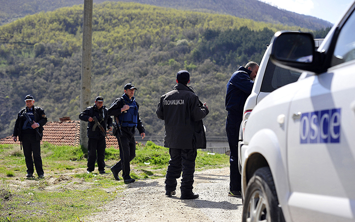 Police officers guard a check point as a vehicle of the Organization for Security and Co-operation in Europe (SCE) passes. 