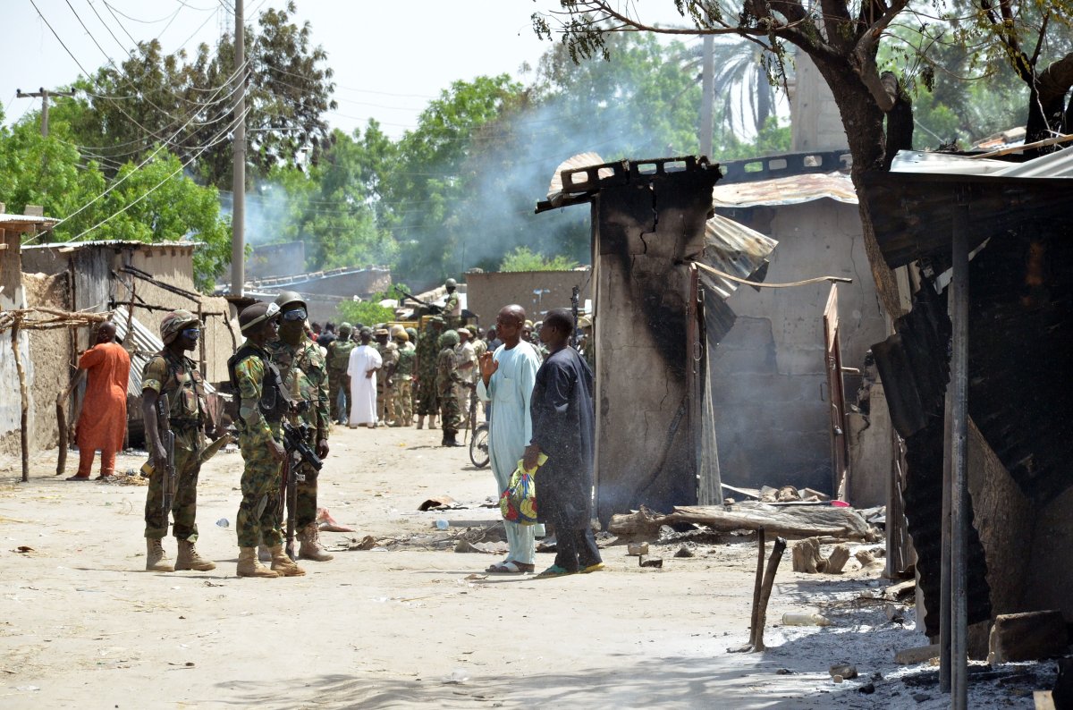 Soldiers speak to people standing away from houses burnt by Boko Haram Islamists near Maiduguri, northeast Nigeria. 