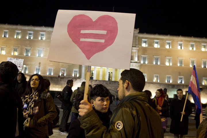 Gay rights supporters gather outside Greece's Parliament to voice approval of a civil partnership bill being debated by lawmakers, in central Athens, on Tuesday, Dec. 22, 2015.