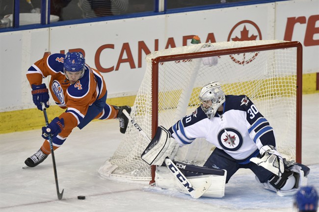 Winnipeg Jets goalie Connor Hellebuyck, covers the net as Edmonton Oilers' Talor Hall controls the puck during first period NHL action in Edmonton, Alta., on Monday, December 21, 2015.