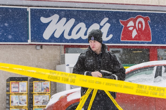 A police officer removes crime scene tape at a Mac's convenience store in Edmonton on Friday, December 18, 2015.